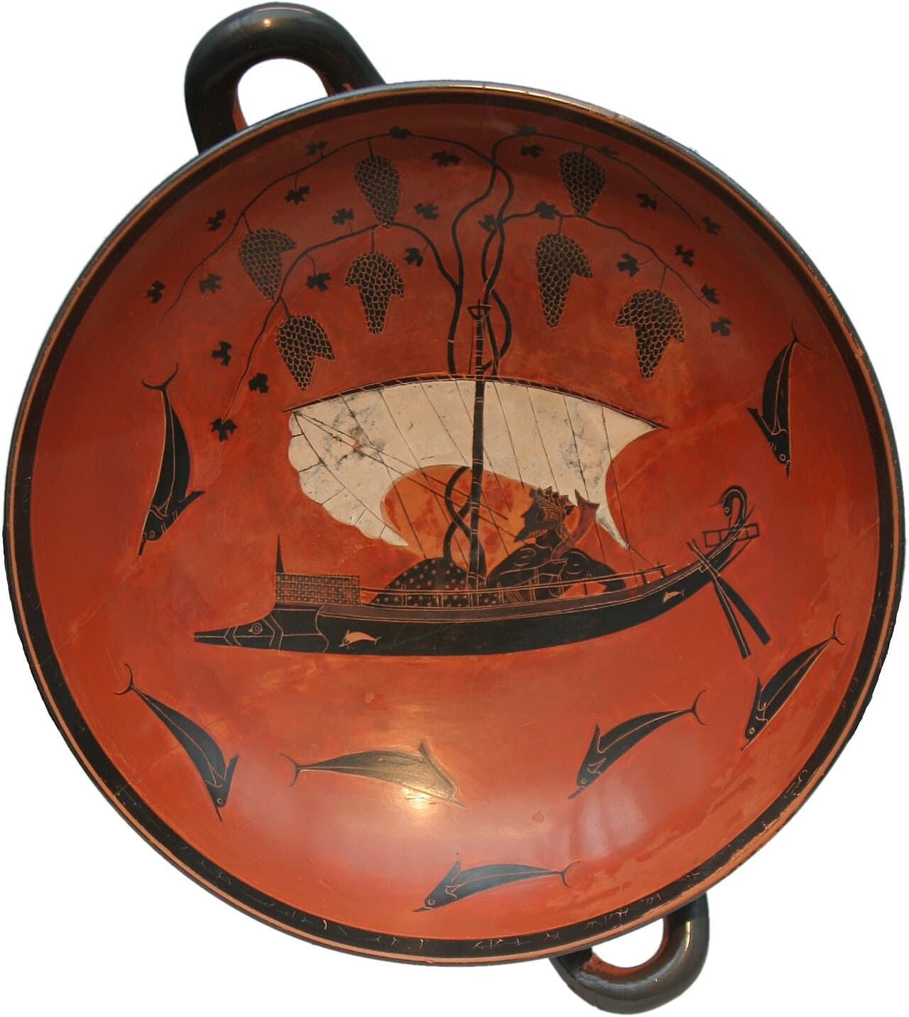 Dionysus reclining in a ship whose mast is wreathed in grapevines, surrounded by dolphins: the interior of a Greek drinking cup, about 530 BCE.